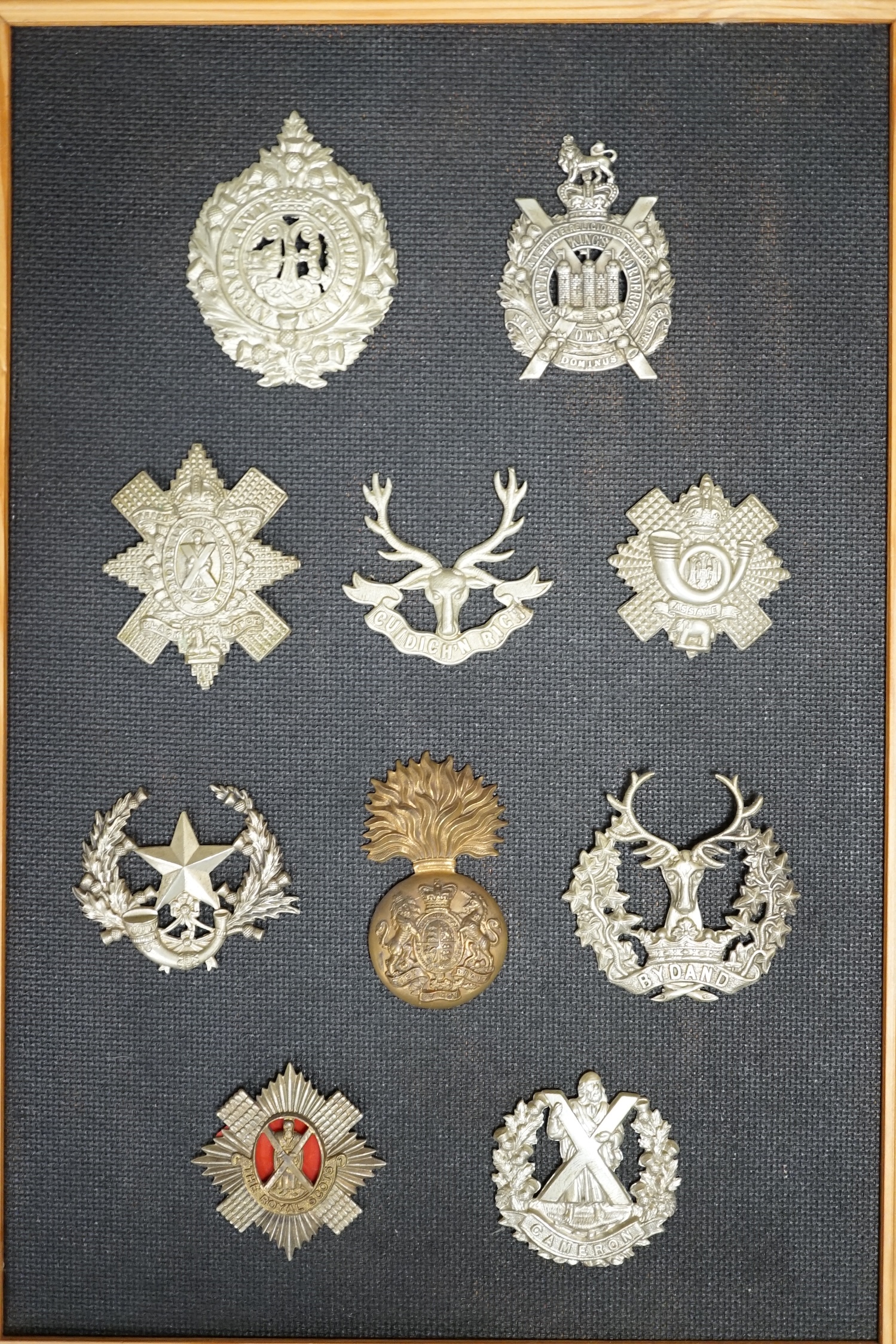 Ten military cap and Glengarry badges mounted on a board including; The King’s Own Scottish Borderers, the Argyle and Sutherland Regiment, the Royal Scots, the Gordon Highlanders, The Queen’s Own Cameron Highlanders, etc